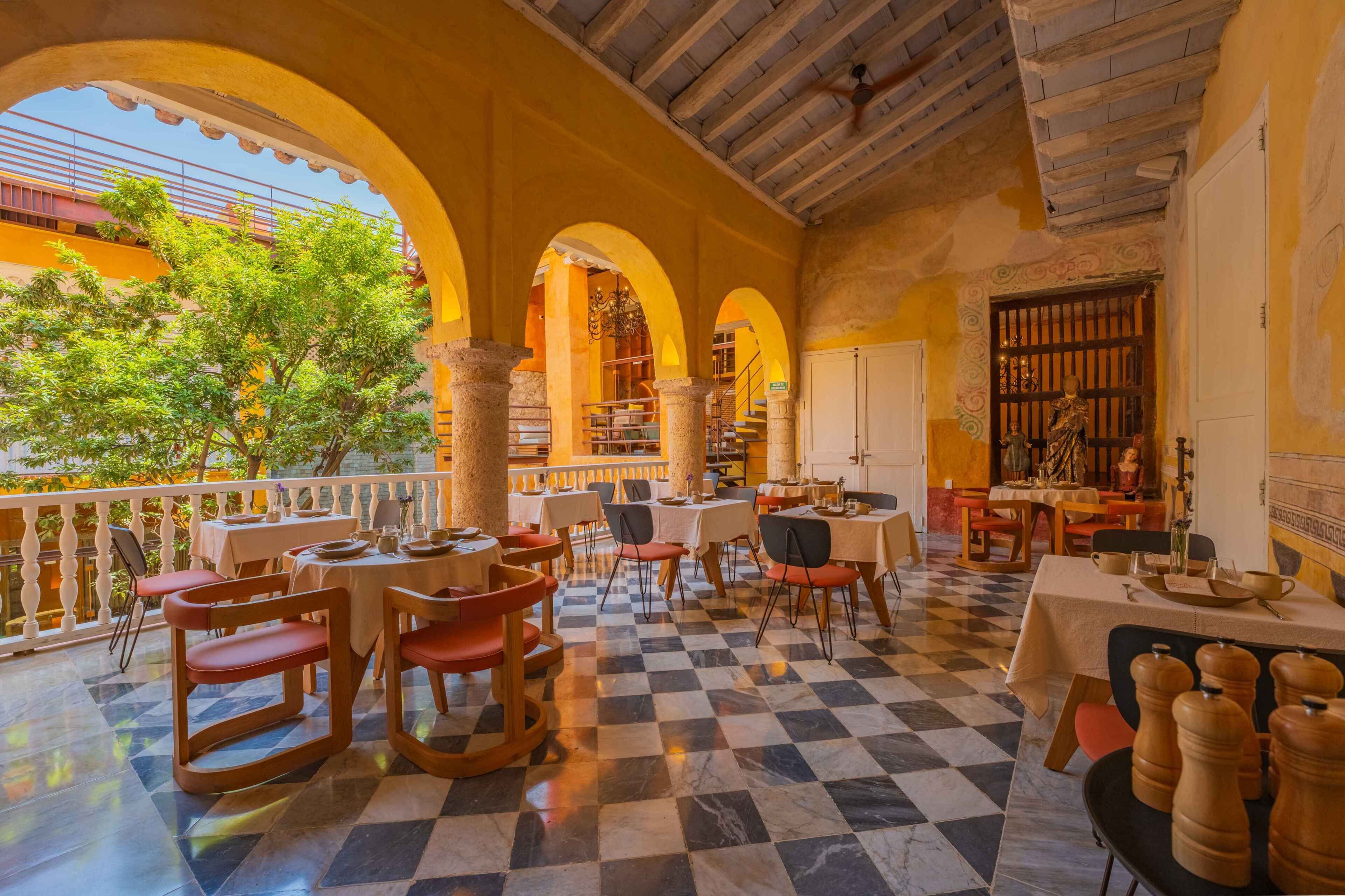 A restaurant with outdoor seating, checkered flooring, and a view of greenery.