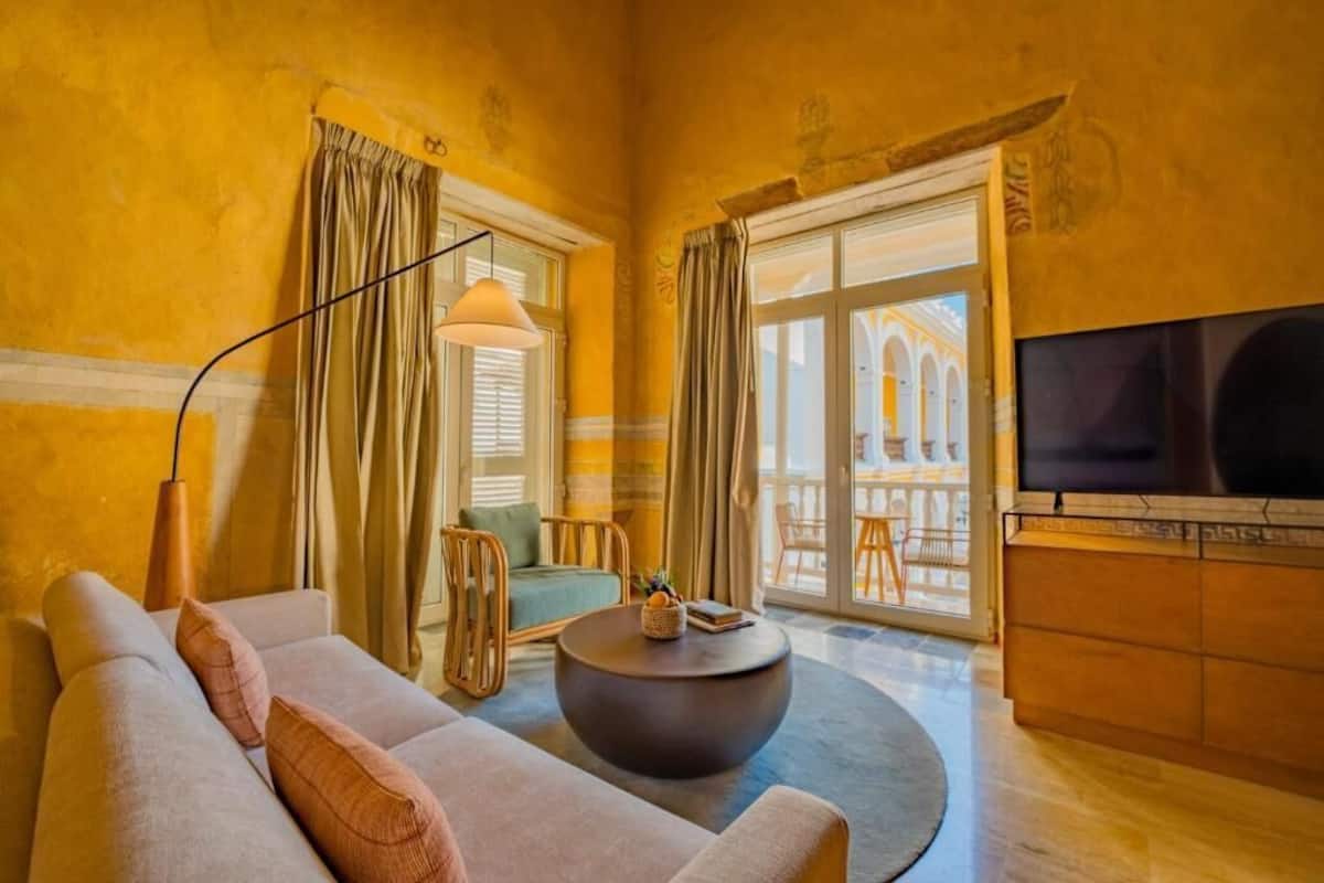 A living room with a sofa, a round coffee table, a television, and a view of an outdoor balcony.