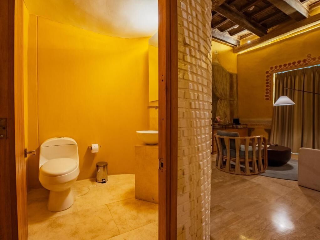 Un baño con inodoro, lavamanos y un pequeño cubo de basura.