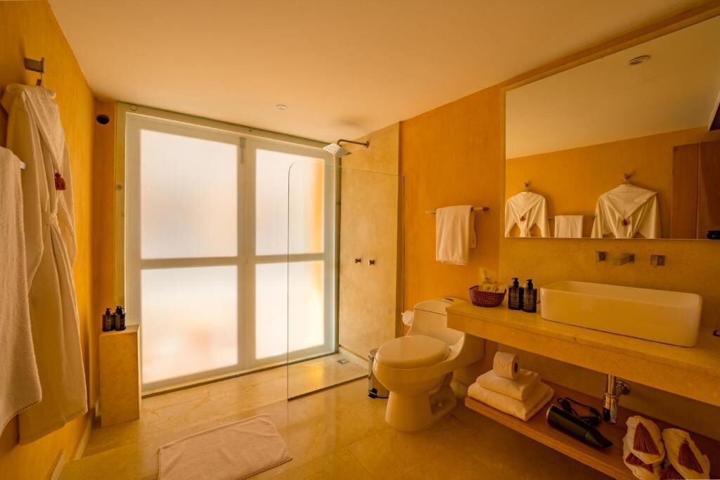 A bathroom with a shower, toilet, sink, and a large mirror.