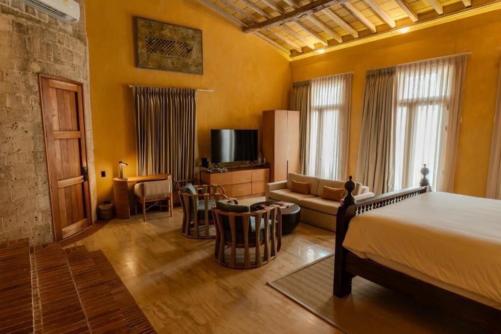 A room with a bed, a TV, a sofa, a desk, and a chair.