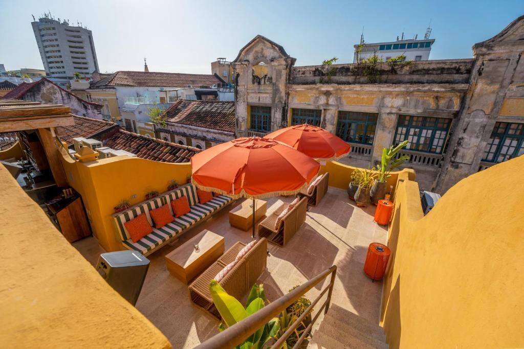Une terrasse sur le toit avec des sièges extérieurs, un escalier et une vue sur des bâtiments historiques.