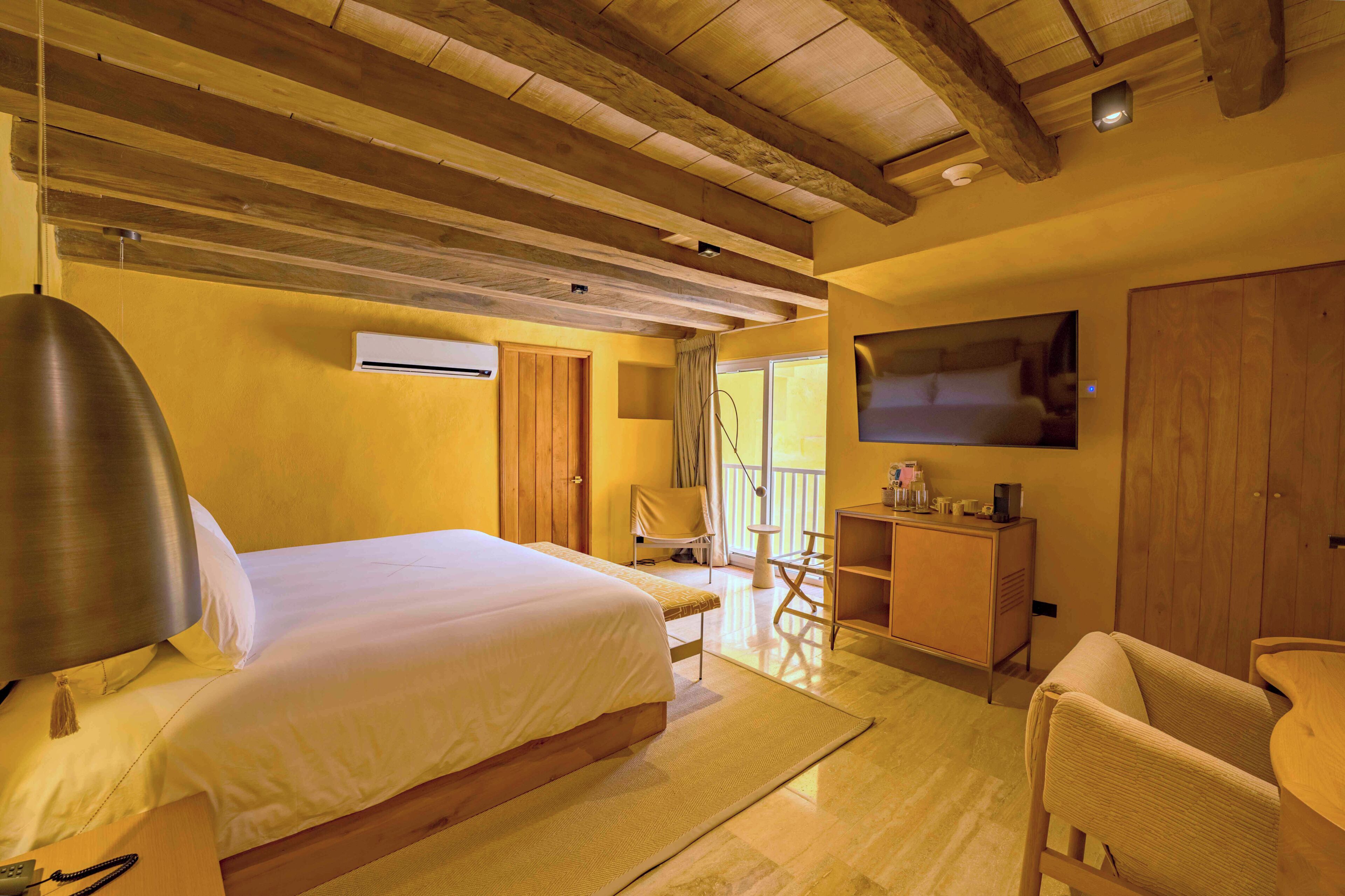 Una habitación de hotel con cama, escritorio, silla, televisor y armario.