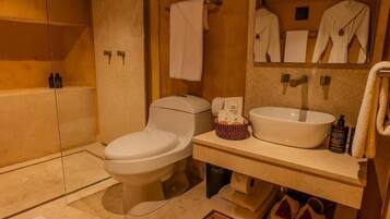 A bathroom with a toilet, sink, and mirror. There are towels and toiletries on the counter.