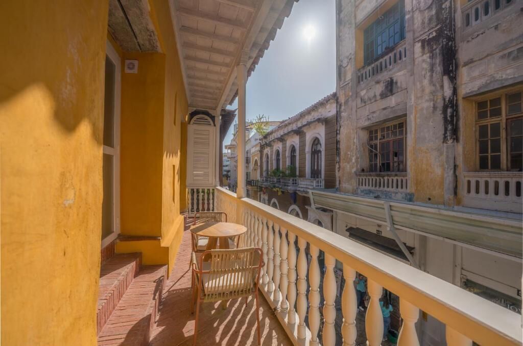 Un balcón con vistas a edificios históricos, una pequeña mesa y dos sillas.