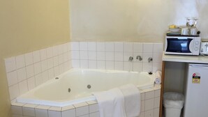 Un baño con bañera, microondas y refrigerador.