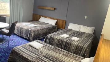 Quarto de hotel com duas camas, uma mesinha e uma cadeira.