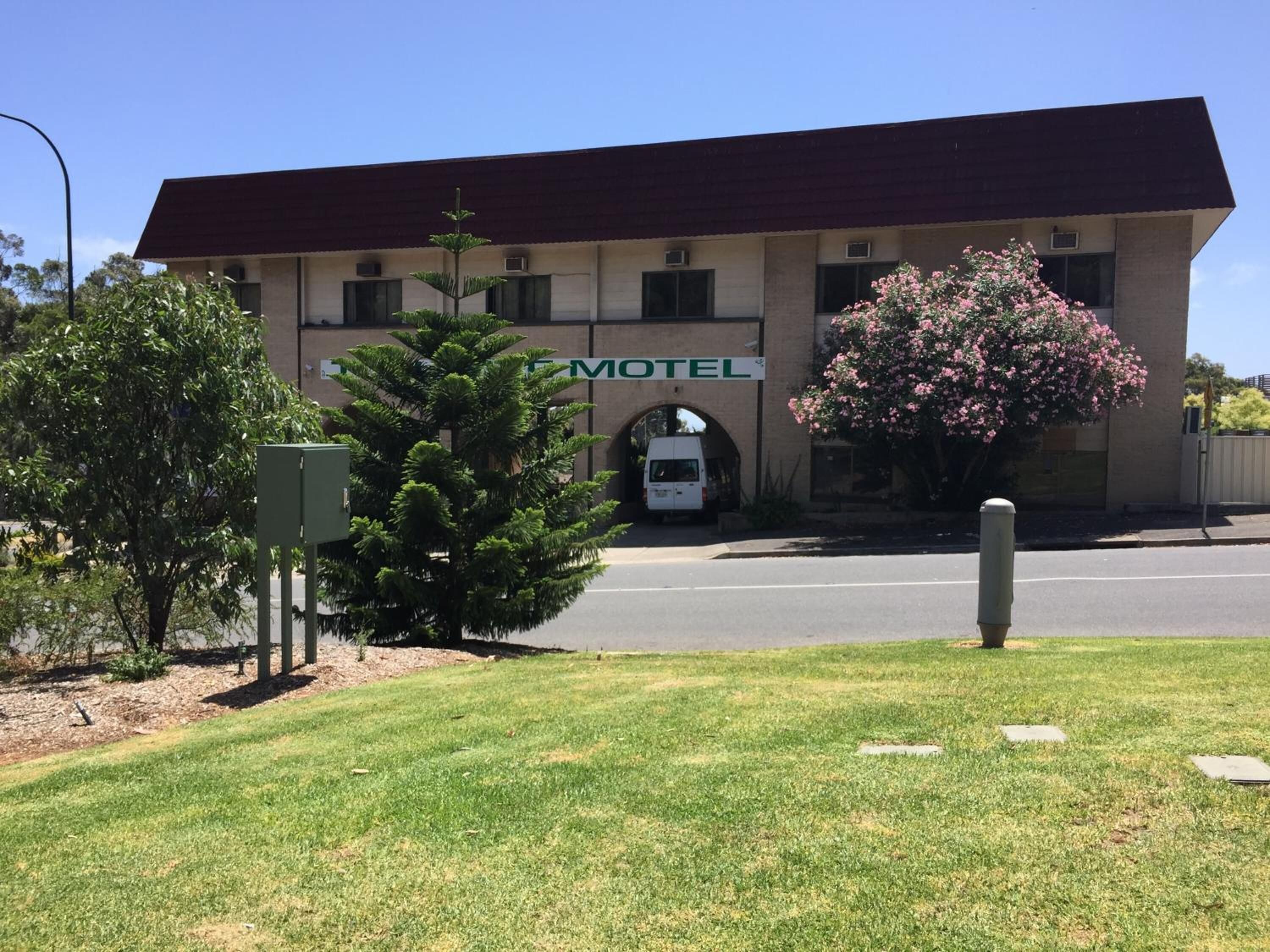 Un motel con techo rojo, un letrero que dice "Motel" y un estacionamiento al frente.