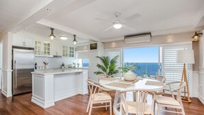 Una cucina moderna con mobili bianchi, un frigorifero in acciaio inossidabile e un'area pranzo con un tavolo rotondo e sedie.