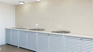 A modern kitchen with three sinks, a countertop, and overhead lighting.