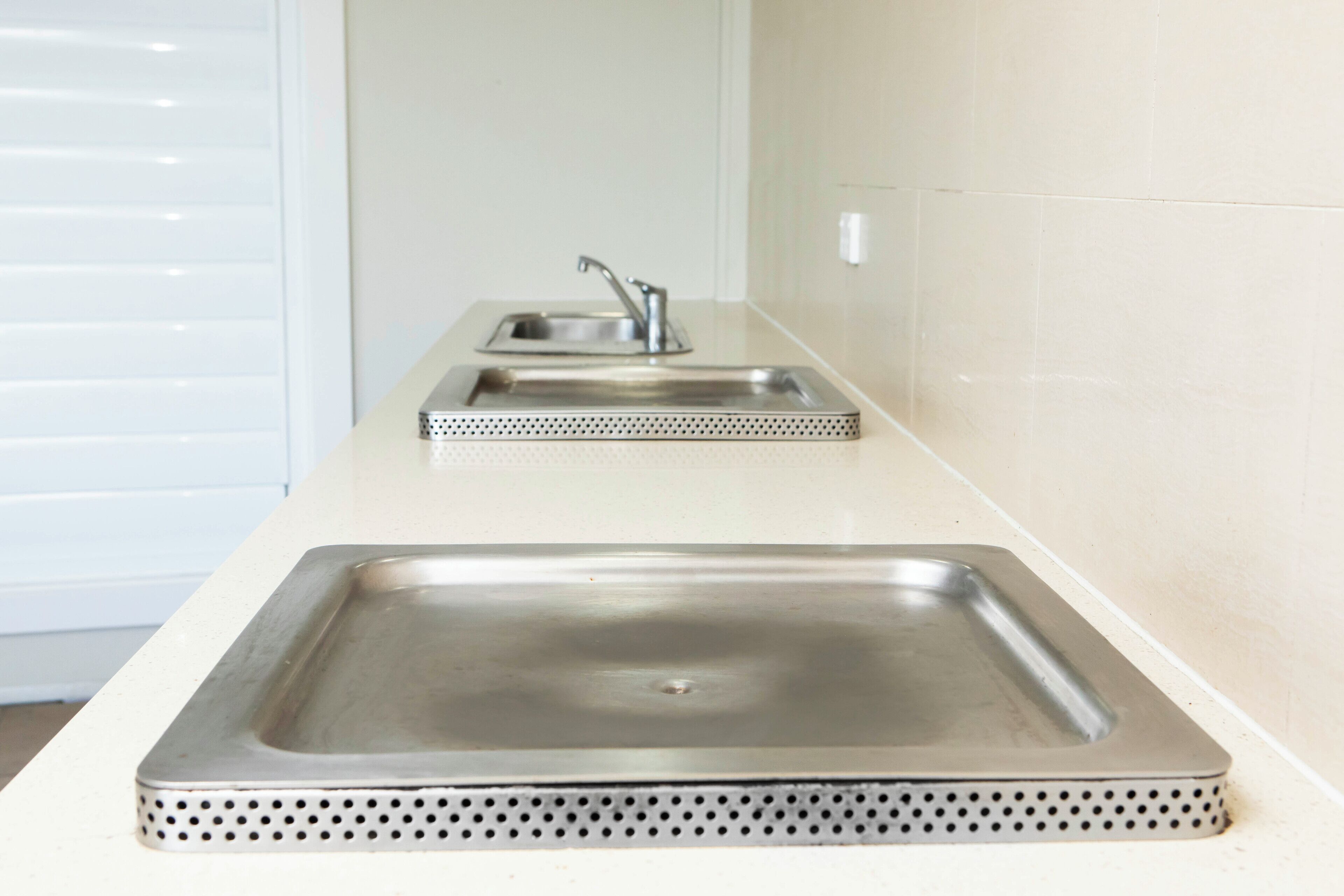 A kitchen with a stainless steel sink and a matching backsplash.