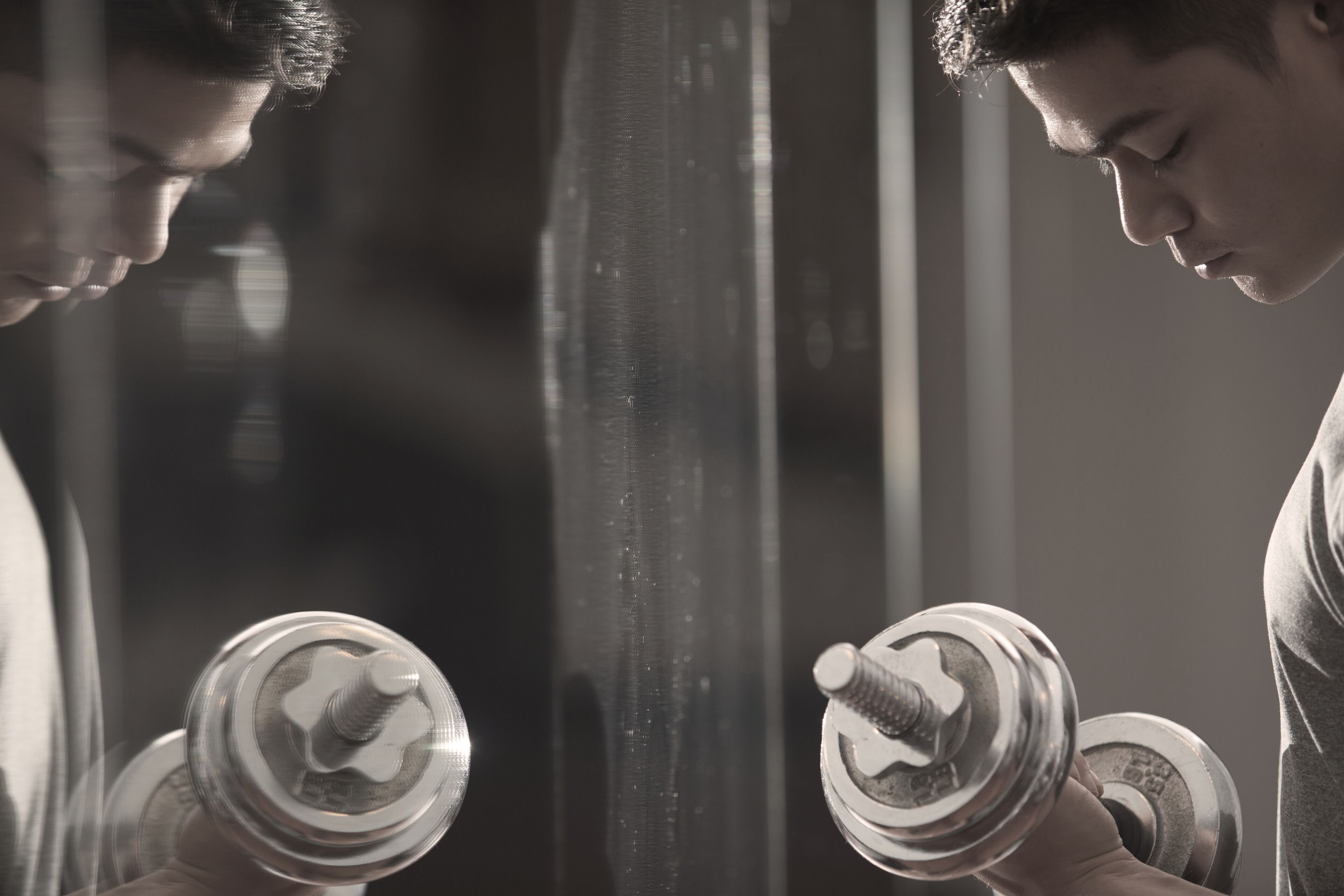 A person holding a dumbbell in front of a mirror.