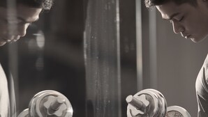 Une personne tenant un haltère devant un miroir.