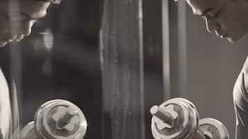 A person holding a dumbbell in front of a mirror.