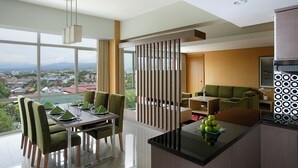 A modern hotel room with a dining area, a seating area, and a kitchen. - Hotel Santika Palu (Palu)