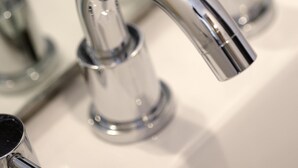 Un robinet chromé doté d’un bec courbé, un évier et un miroir.