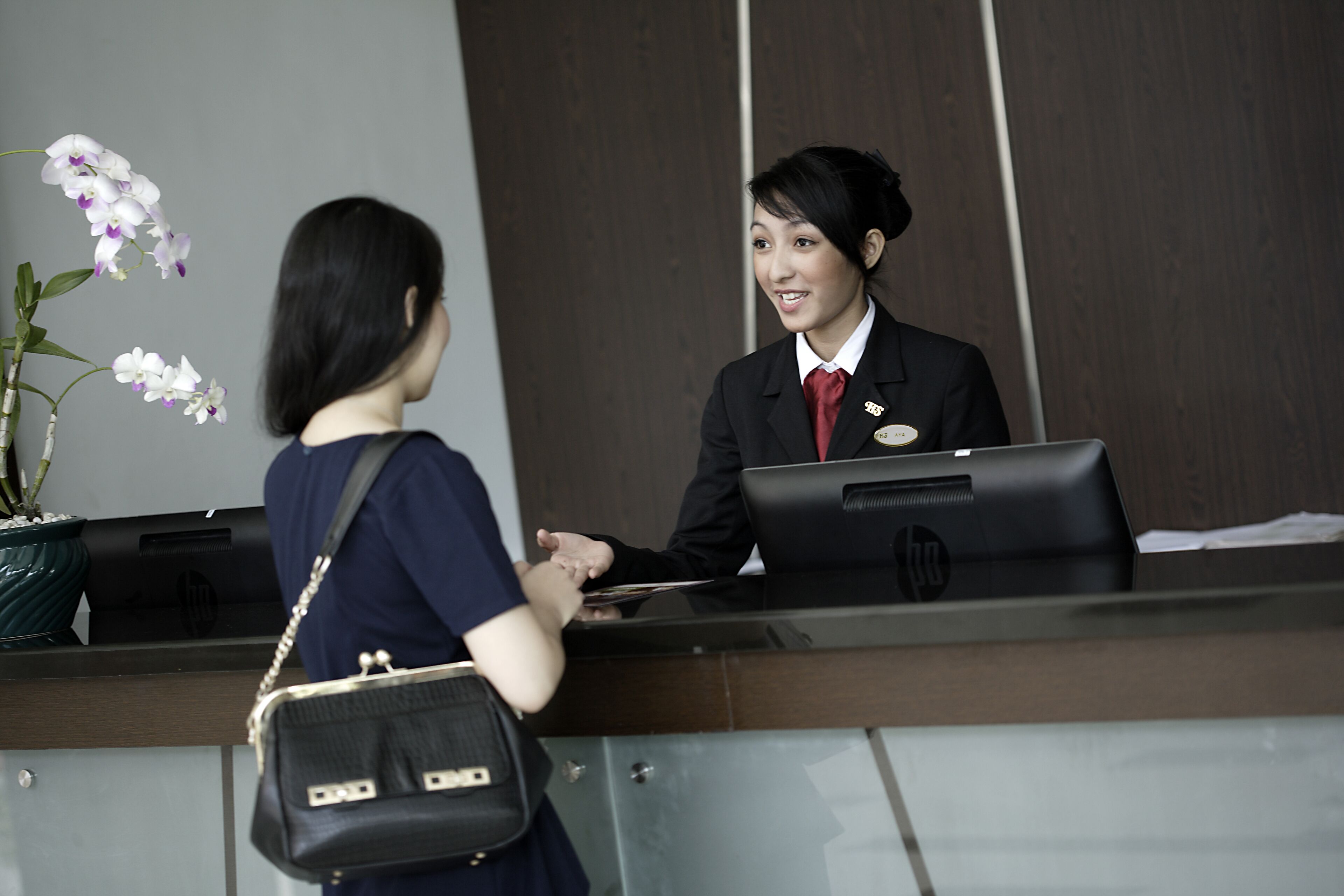 Una recepción con una recepcionista y una mujer.