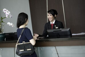 A reception desk with a woman and a receptionist. - Hotel Santika Palu (Palu)