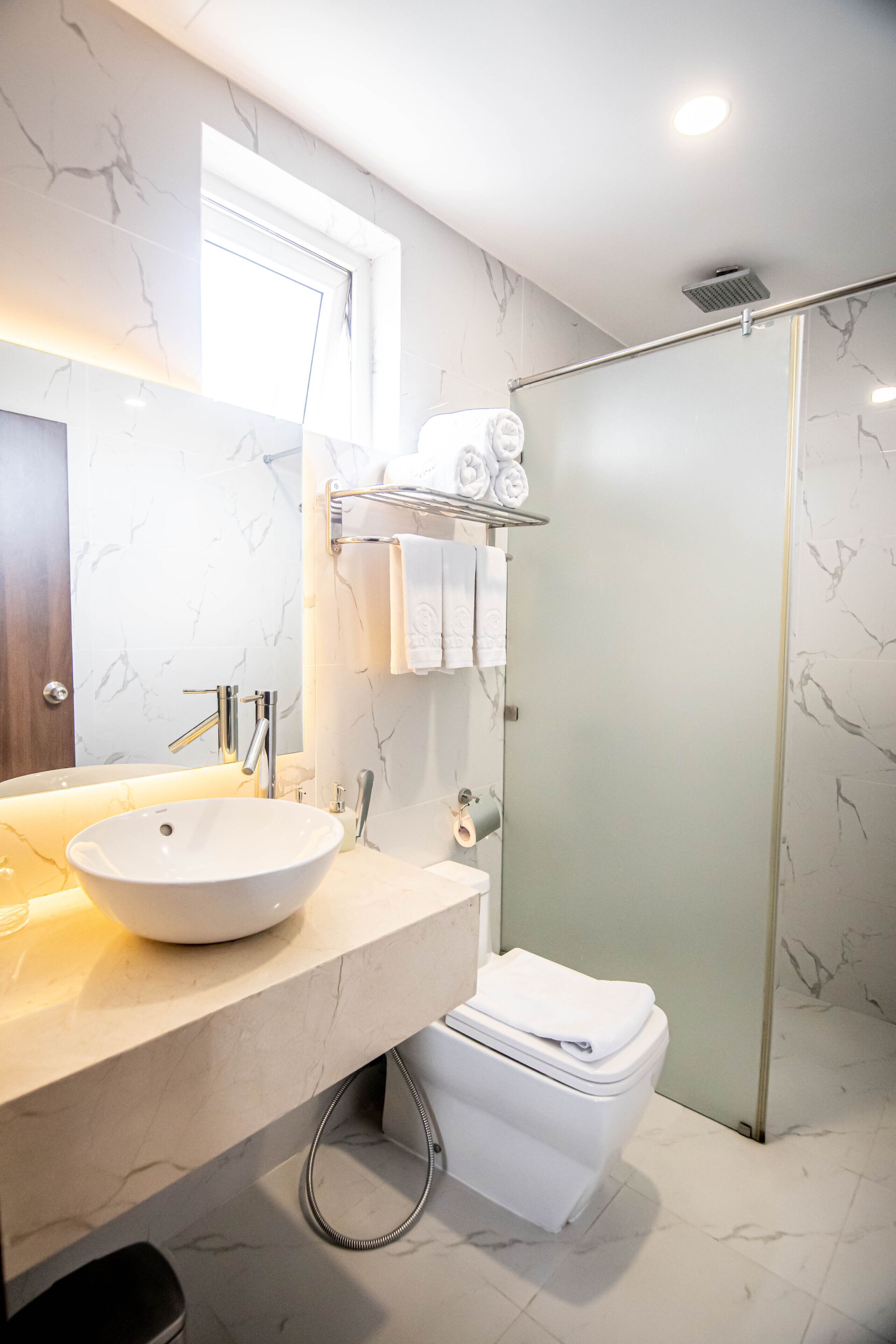 A modern bathroom with a large sink, a toilet, and a glass-enclosed shower.