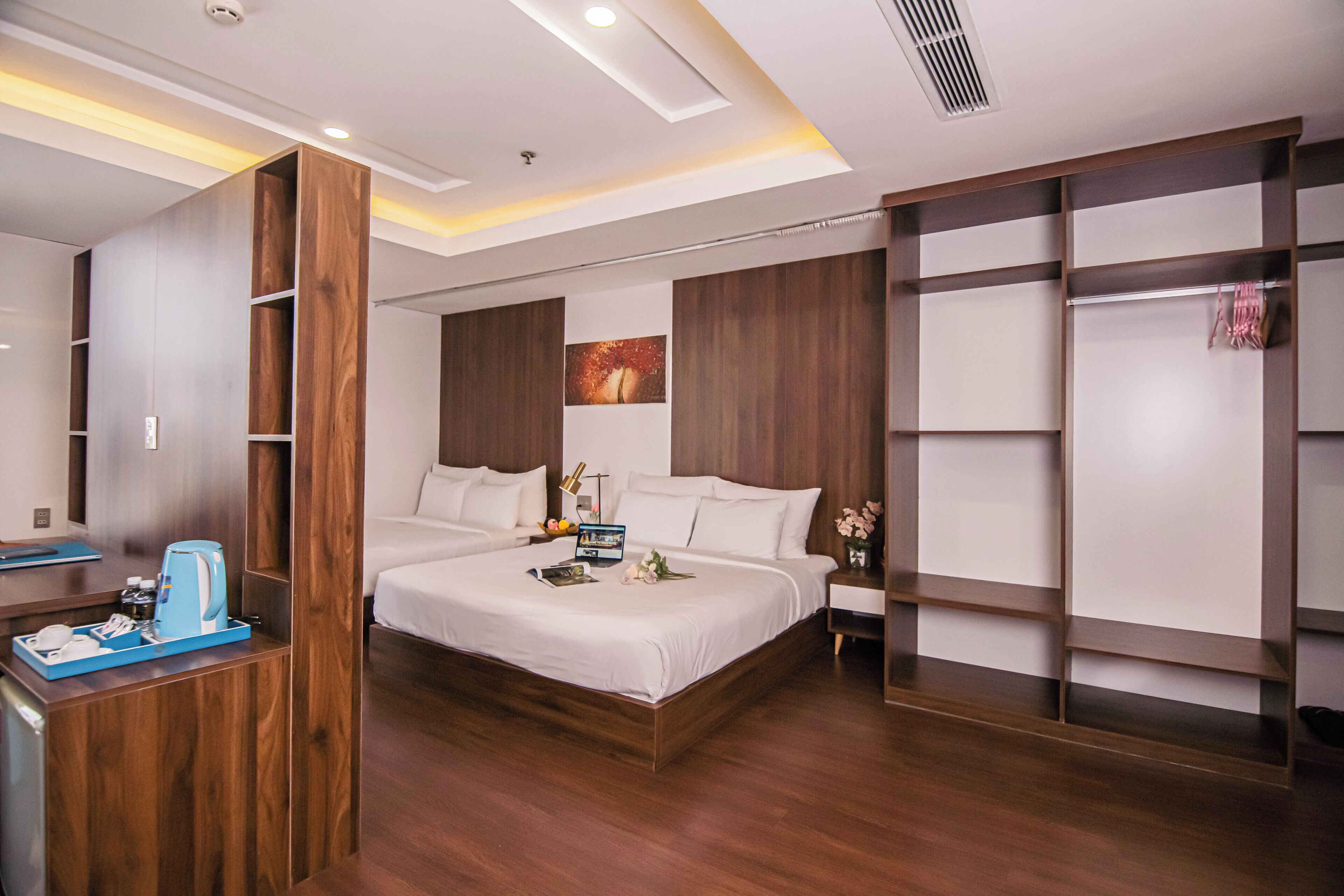 Una habitación de hotel moderna con una cama grande, un armario de madera y una mesita de noche con cafetera.