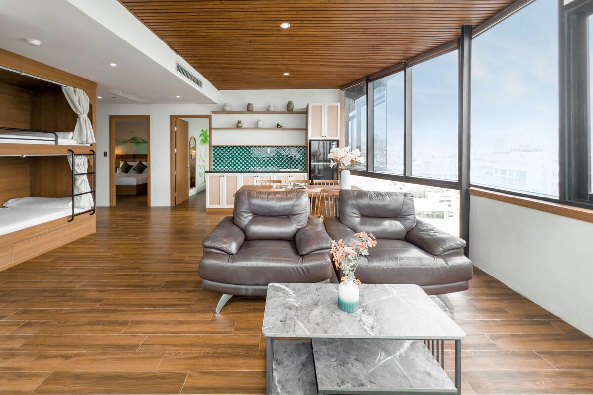 A modern living room with a wooden ceiling, a sofa, a coffee table, and a view of the city through large windows.