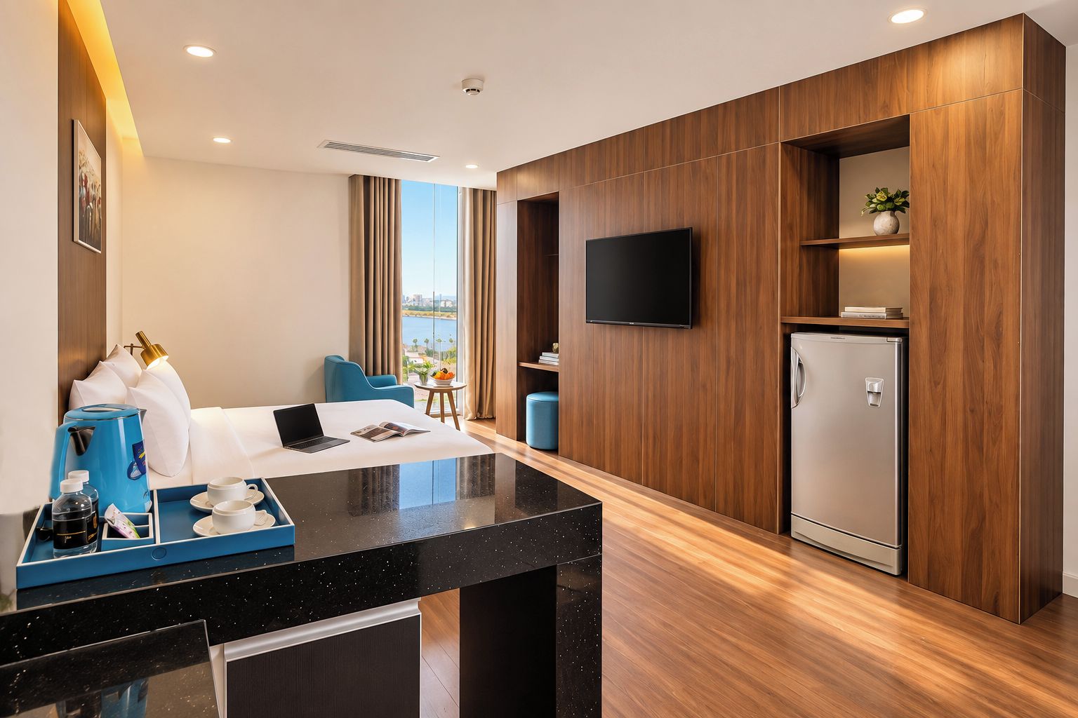 Habitación de hotel moderna con televisión de pantalla plana, minibar, zona de estar con sofá y sillones, y vistas a la ciudad.