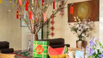 A table with a vase of branches, a green gift box, a woven basket, and a decorative item.