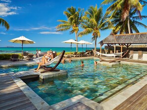 Un espace piscine avec une eau claire, des chaises longues et des parasols.