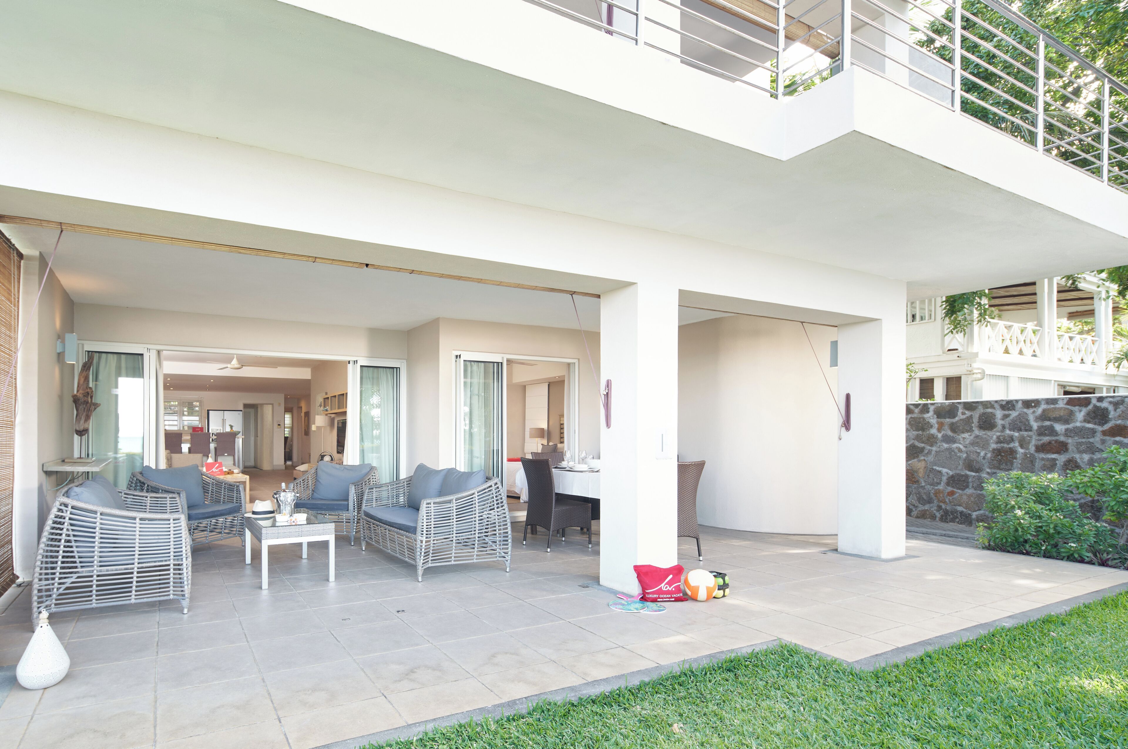 Un espacio exterior moderno con mobiliario de mimbre, una mesa de comedor y una pared de piedra.