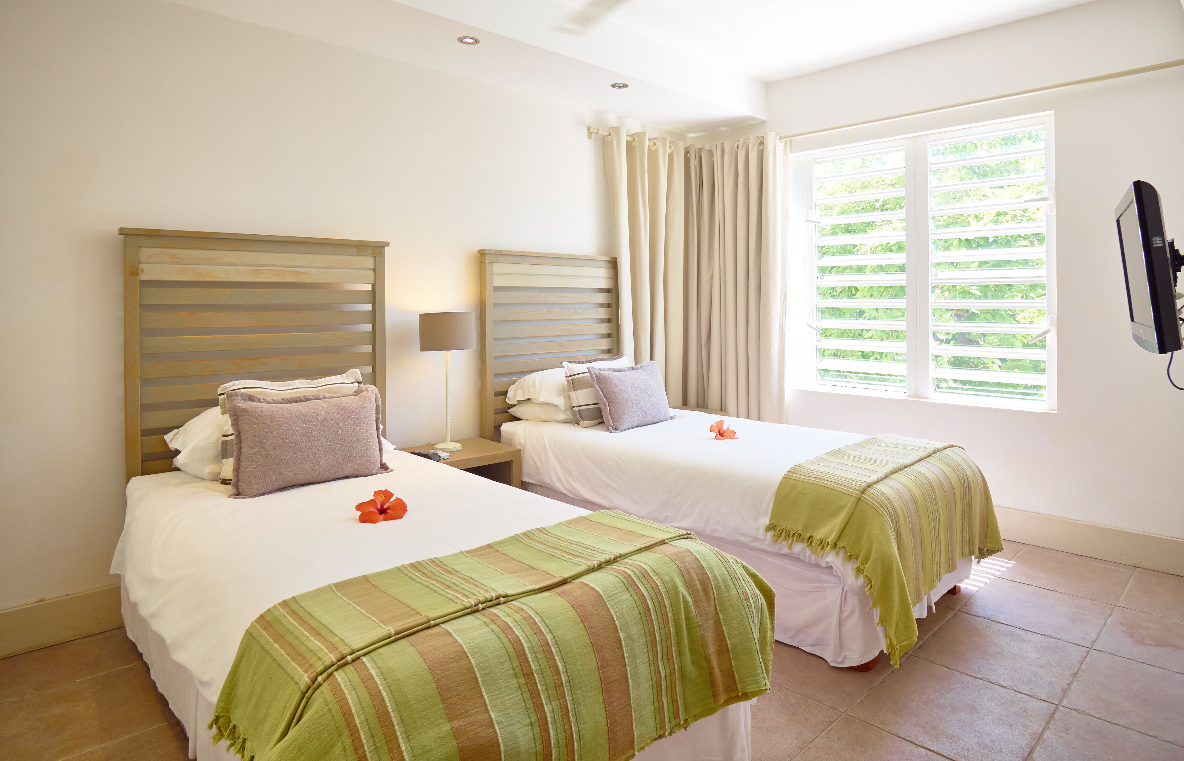 A hotel room with two beds, a TV, and a window with curtains.