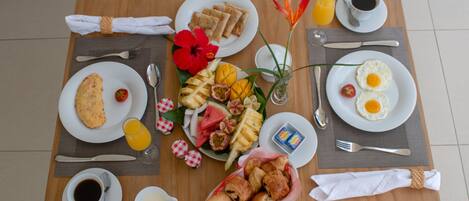 A breakfast table with plates of food, including eggs, toast, and fruit, along with cups of coffee and juice.