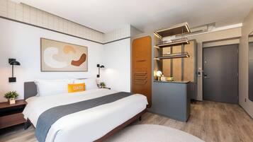 A modern hotel room with a large bed, bedside tables, a desk, and a wardrobe.