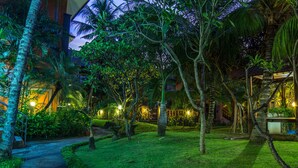 A well-lit garden pathway leading to a building with a covered outdoor area. - Bakung Beach Resort (Kuta)