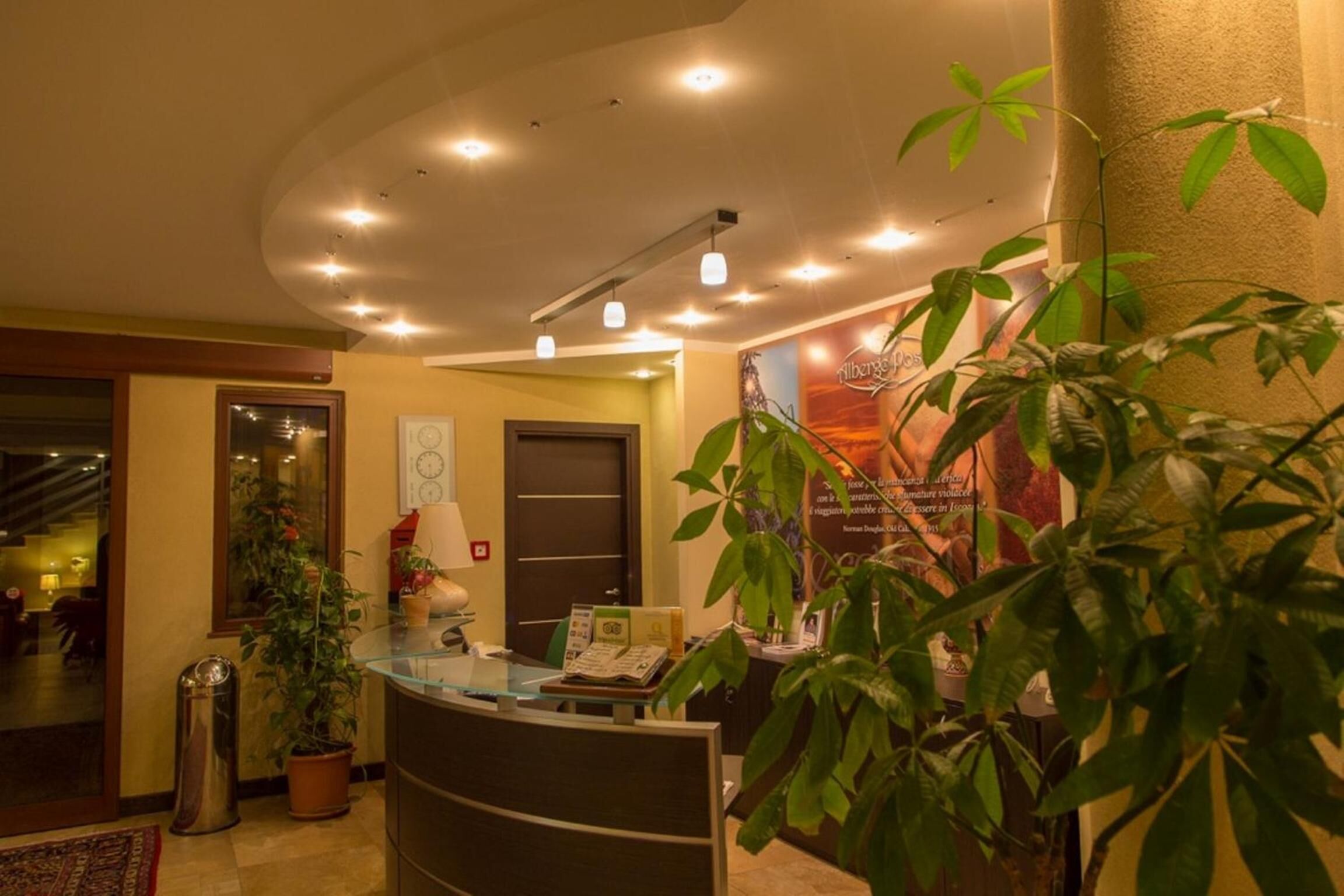 A reception area with a desk, potted plants, and a poster on the wall.
