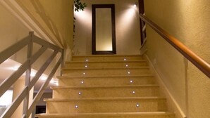 A staircase with a handrail and a light fixture on the wall. - Albergo della Posta (Taverna)
