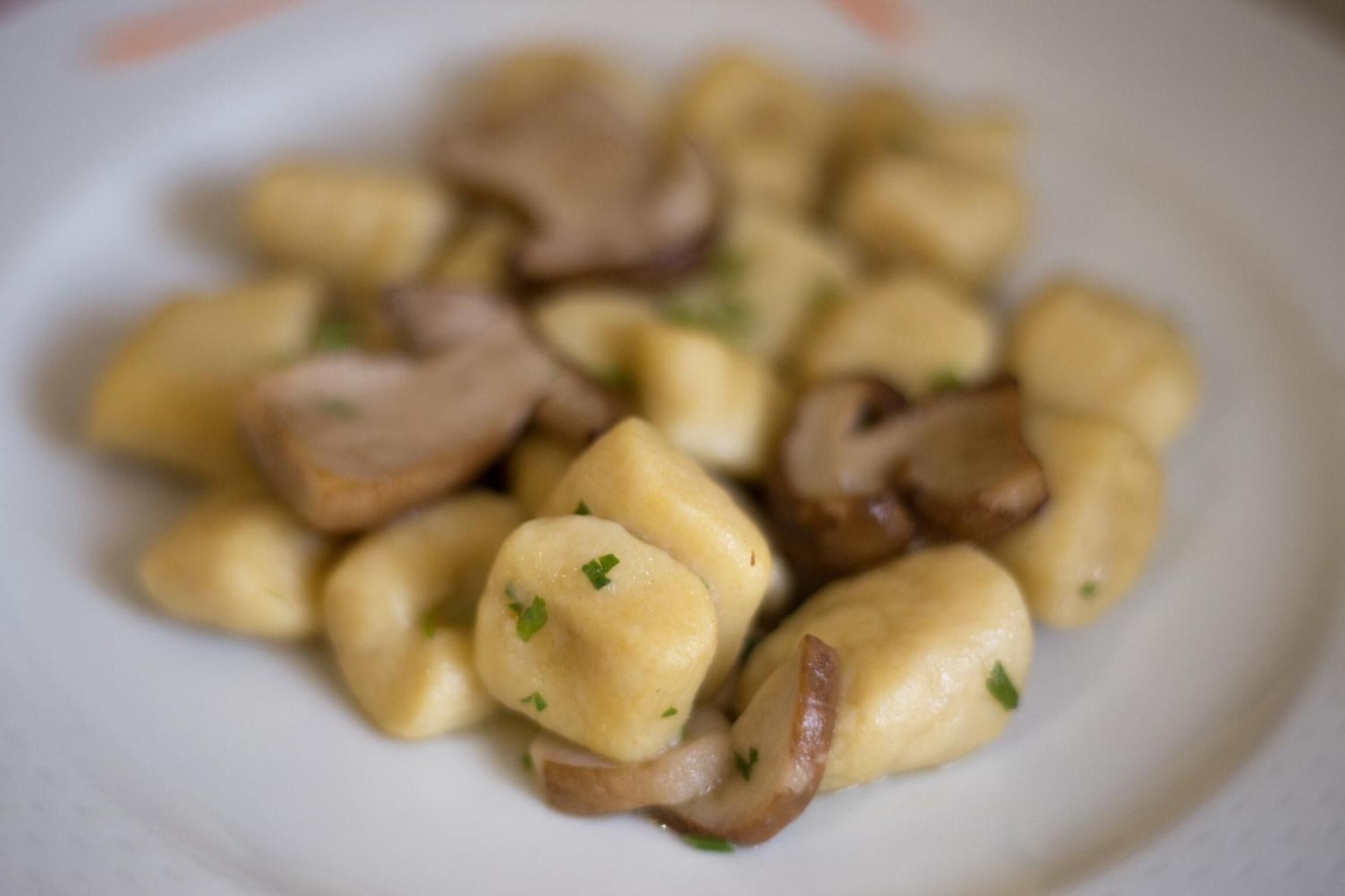 Un plato de ñoquis con champiñones y hierbas.