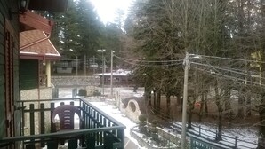 A view from a balcony overlooking a snowy landscape with a stone bridge, trees, and a building with a stone wall and a red roof. - Albergo della Posta (Taverna)