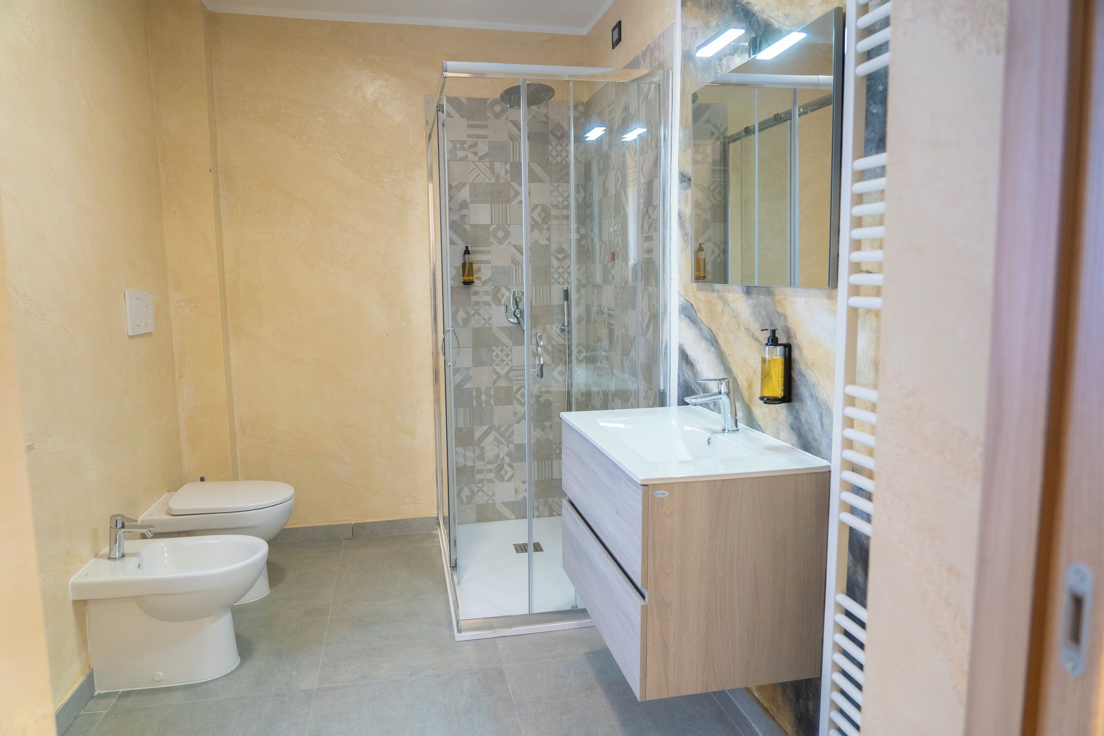 Een moderne badkamer met een douchecabine van glas, een toilet en een wastafel met spiegel.