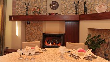 Comedor con chimenea, pared de piedra y un reloj.