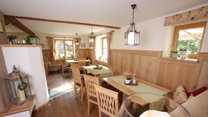 A cozy dining area with wooden furniture, pendant lights, and a view of the outdoors through large windows. - Pension Schweizerhaus (Weyarn)