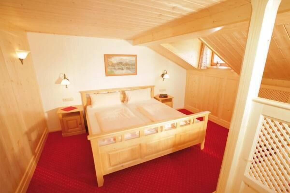 A wooden-framed bedroom with a bed, two bedside tables, and a red carpet.