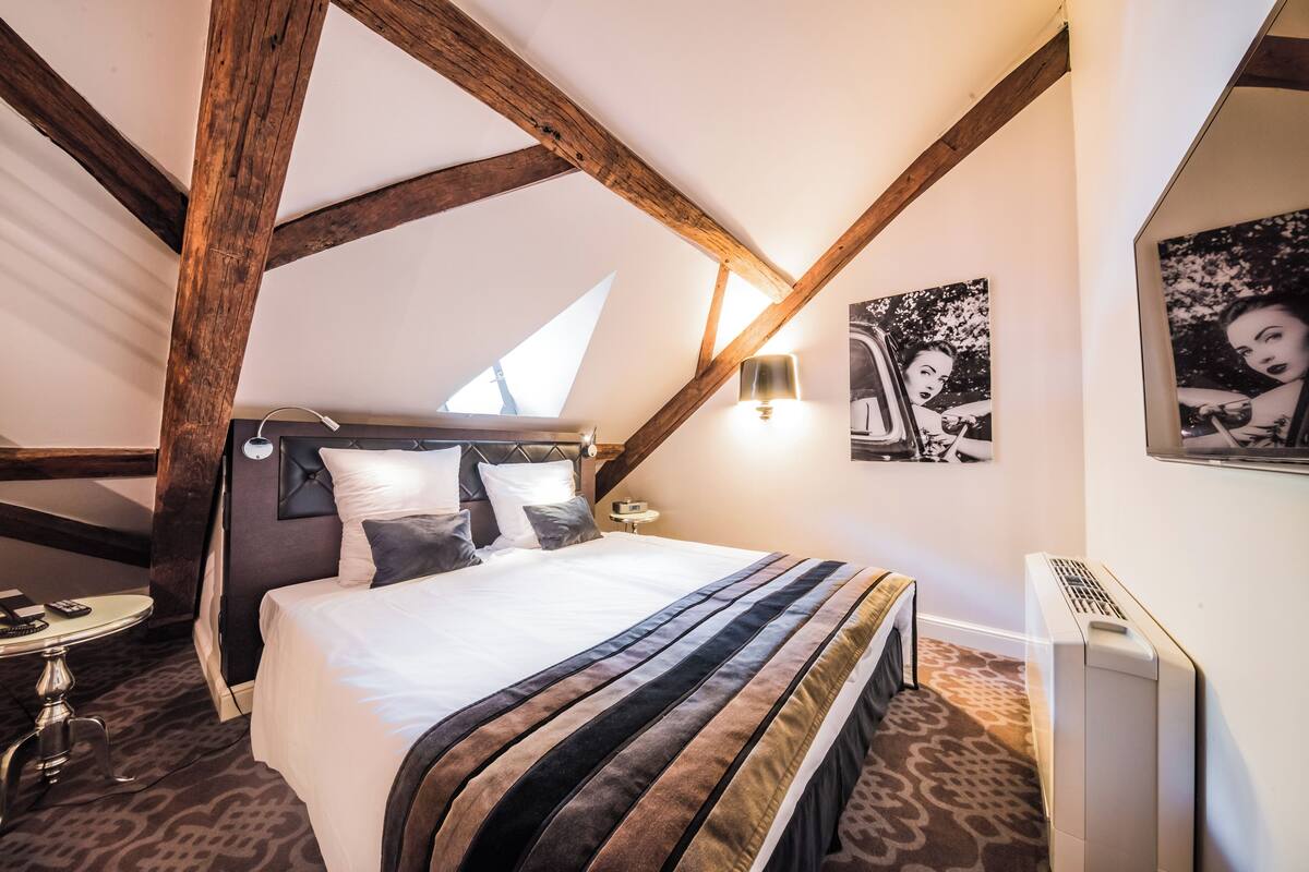A bedroom with a large bed, a small table, a lamp, and a radiator.