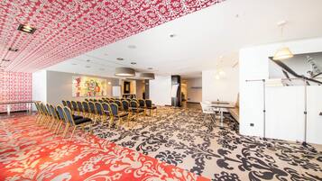 A conference room with a patterned carpet, rows of chairs, a whiteboard, and a large window.