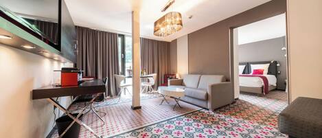 A modern hotel room with a large bed, a sofa, a desk, and a dining area.