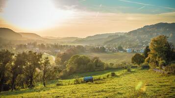A rural landscape with rolling hills, a small blue water tank, and a few scattered houses.