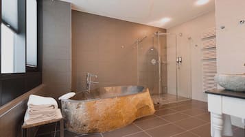 A modern bathroom with a freestanding bathtub, a glass-enclosed shower, and a vanity with a stone basin.