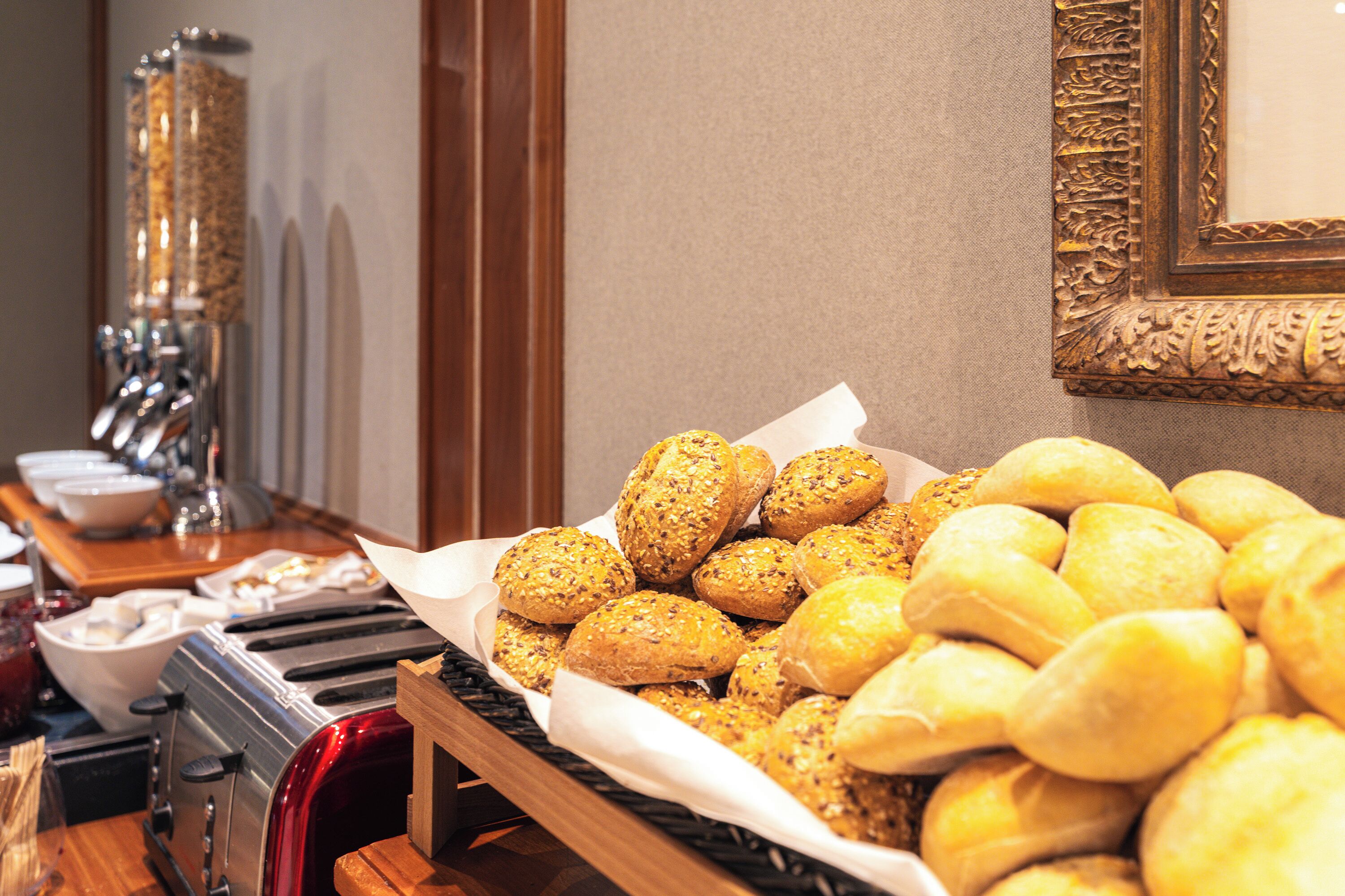 A buffet table with various breads and pastries, a toaster, and a coffee maker.