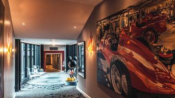 Un couloir d’hôtel orné d’une grande fresque représentant une voiture de course, d’une statue de Mickey Mouse et doté d’un aménagement intérieur moderne.