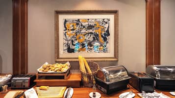 Mesa de desayuno buffet con pan, bollería y un tostador.