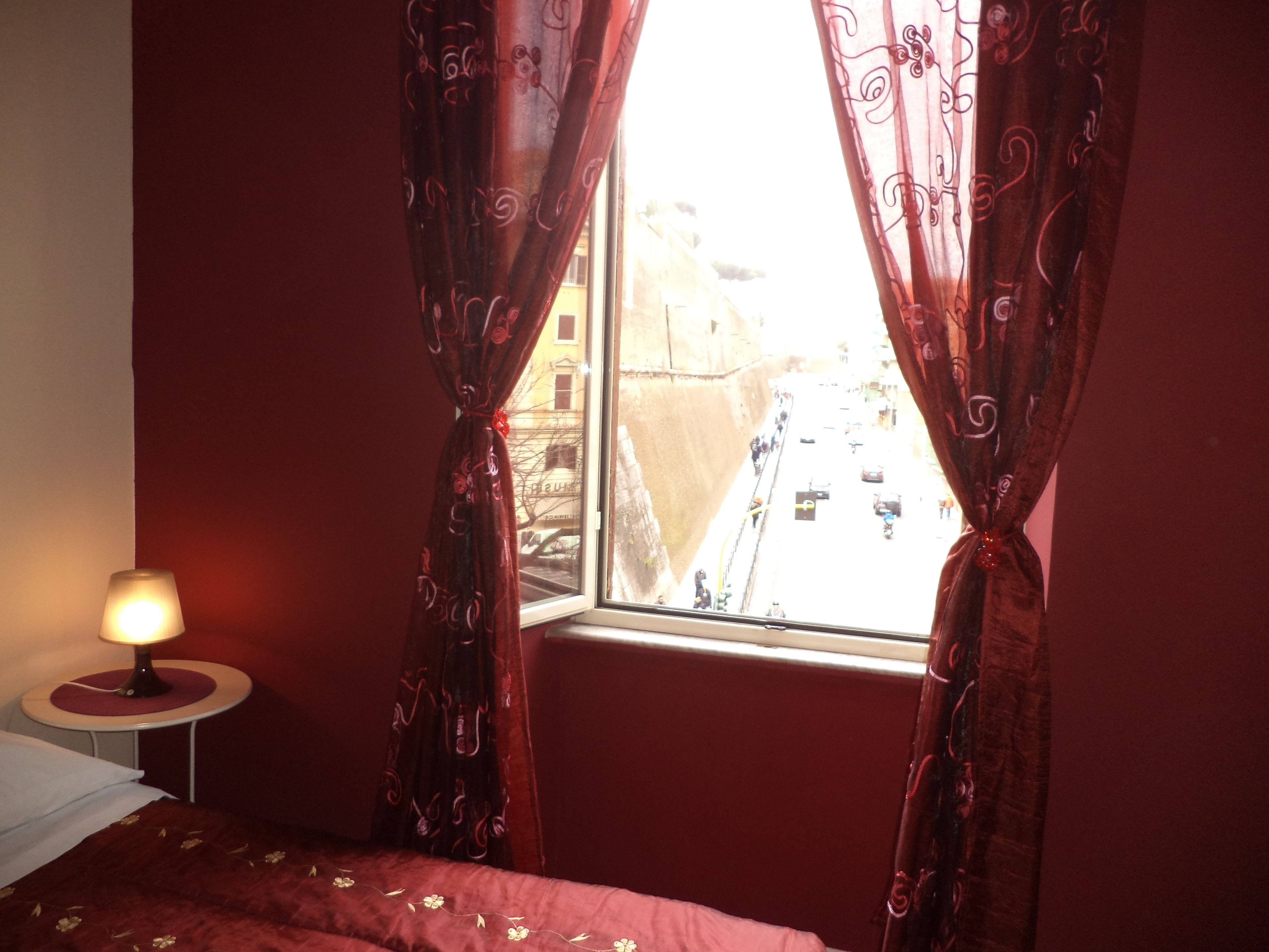 Een kamer met een bed, een lamp en een raam met gordijnen.